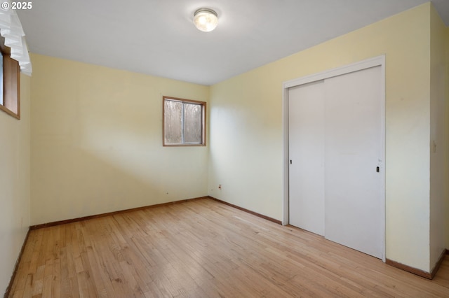 unfurnished bedroom featuring a closet, baseboards, and wood finished floors