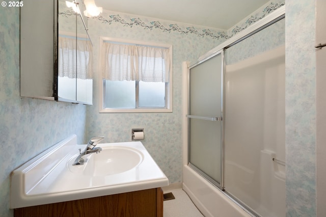 bathroom featuring baseboards, enclosed tub / shower combo, vanity, and wallpapered walls