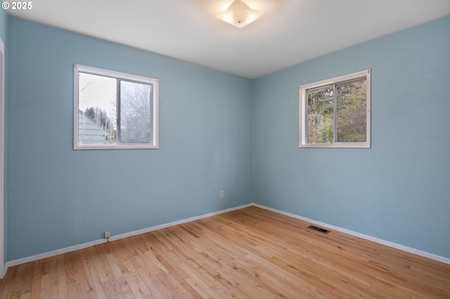 empty room featuring visible vents, baseboards, and wood finished floors