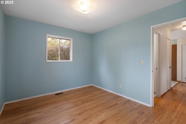 empty room with visible vents, baseboards, and light wood finished floors