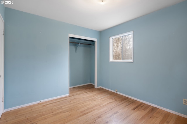 unfurnished bedroom with a closet, baseboards, and wood finished floors