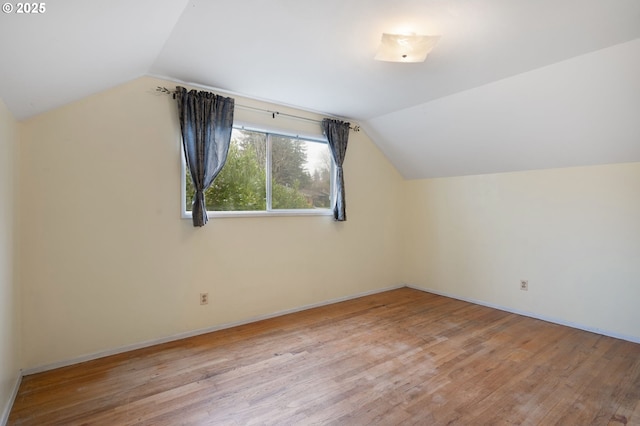 bonus room featuring light wood-type flooring, lofted ceiling, and baseboards