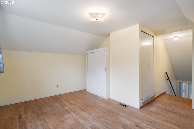 bonus room with visible vents, light wood-style floors, and vaulted ceiling