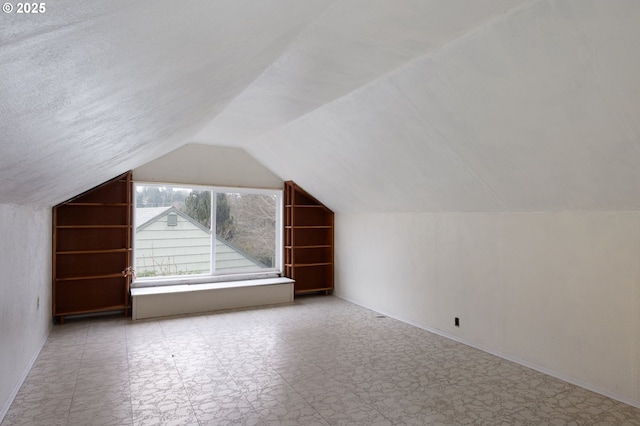 additional living space featuring baseboards and lofted ceiling