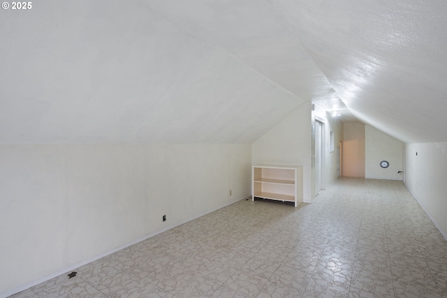 additional living space featuring light floors and vaulted ceiling