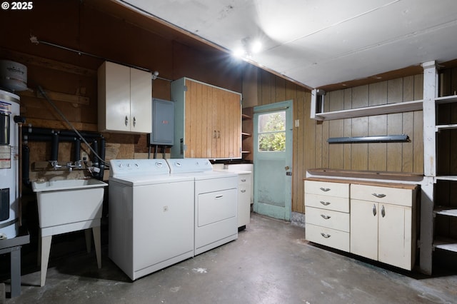 washroom with electric panel, cabinet space, a sink, wood walls, and independent washer and dryer