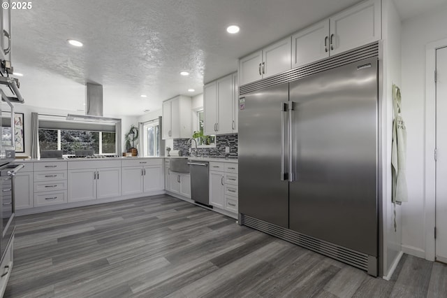 kitchen with a textured ceiling, white cabinets, wood finished floors, and stainless steel appliances