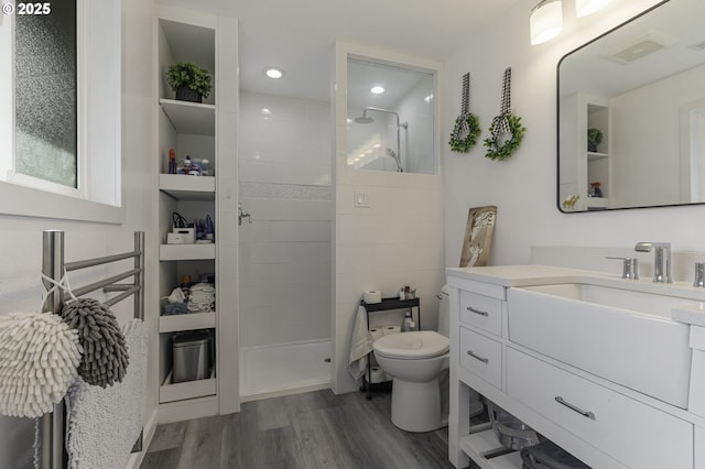 full bathroom featuring toilet, a walk in shower, wood finished floors, recessed lighting, and vanity