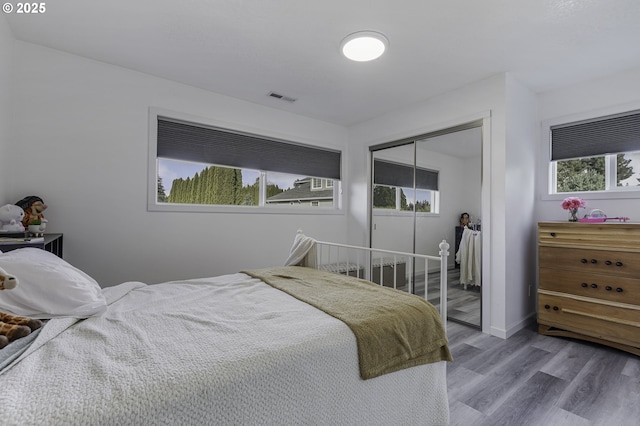 bedroom featuring wood finished floors, visible vents, a closet, and baseboards