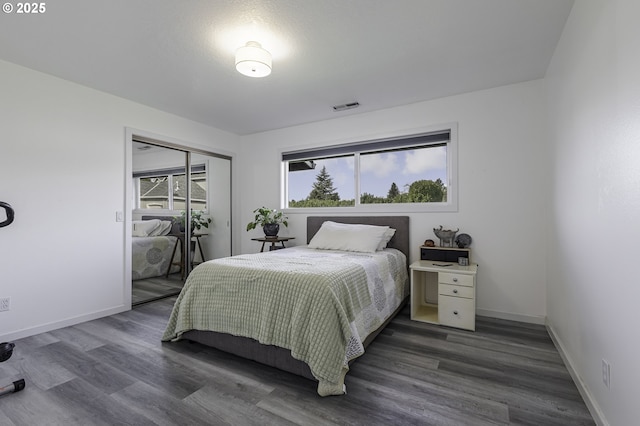 bedroom with a closet, visible vents, baseboards, and wood finished floors