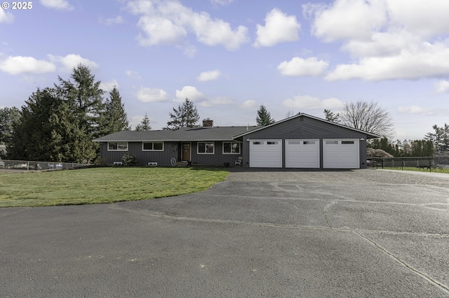 ranch-style home with an attached garage, a front lawn, fence, a chimney, and driveway