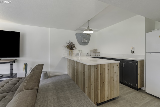 bar featuring baseboards, freestanding refrigerator, vaulted ceiling, a textured ceiling, and light wood-type flooring