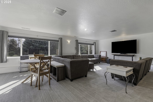 living room featuring visible vents, light colored carpet, and a textured ceiling