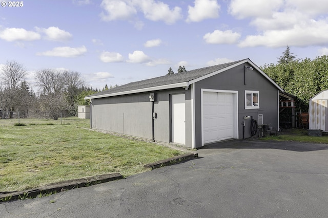 detached garage featuring aphalt driveway and fence