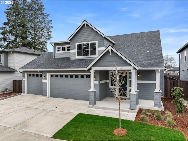 view of front of house with a garage, roof with shingles, driveway, and fence