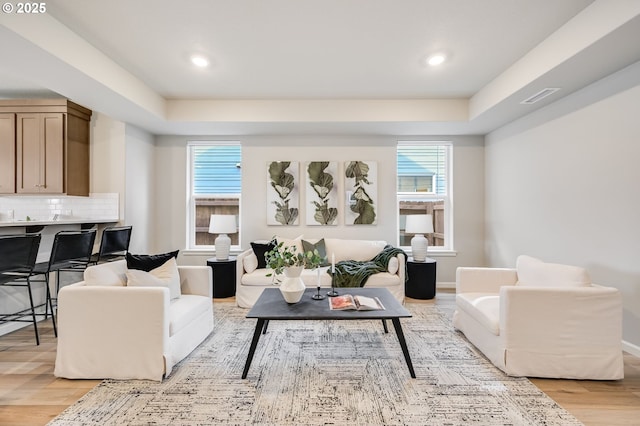 living area with a wealth of natural light, visible vents, and light wood finished floors