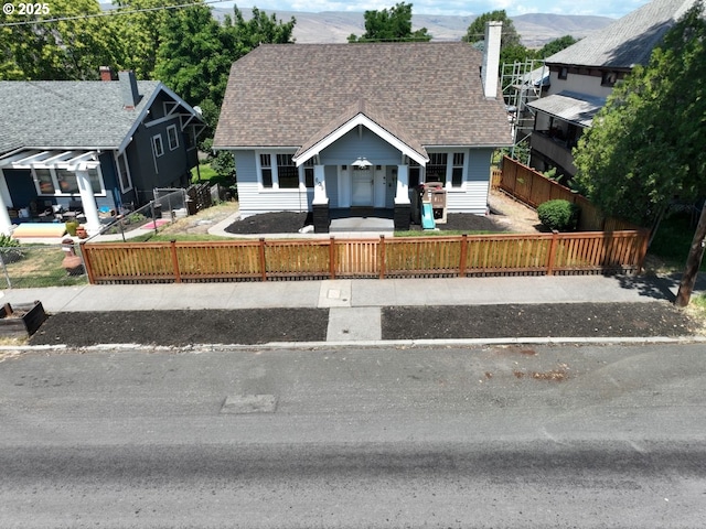 609 E 10th St, The Dalles, OR 97058 - view of front of home featuring covered porch, a fenced front yard, a mountain view, and roof with shingles