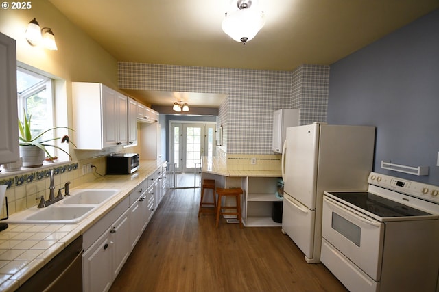 609 E 10th St, The Dalles, OR 97058 - kitchen with stainless steel appliances, tile counters, a sink, dark wood-style flooring, and wallpapered walls