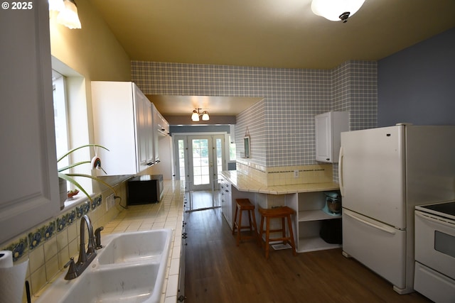 609 E 10th St, The Dalles, OR 97058 - kitchen featuring white appliances, a sink, wood finished floors, white cabinets, and tile counters