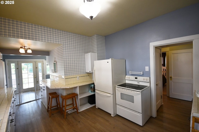 609 E 10th St, The Dalles, OR 97058 - kitchen with white appliances, tile countertops, wallpapered walls, dark wood-type flooring, and a peninsula