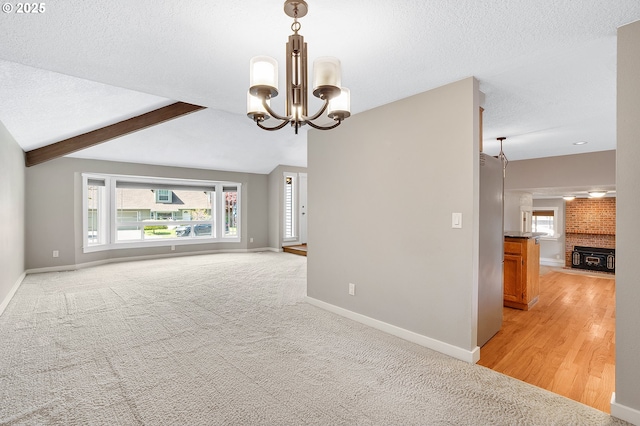 20752 SW 104th Ave, Tualatin, OR 97062 - unfurnished room with healthy amount of natural light, a chandelier, a textured ceiling, light colored carpet, and a brick fireplace