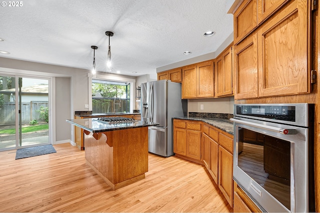 20752 SW 104th Ave, Tualatin, OR 97062 - kitchen with stainless steel appliances, light wood finished floors, a center island, a textured ceiling, and brown cabinets