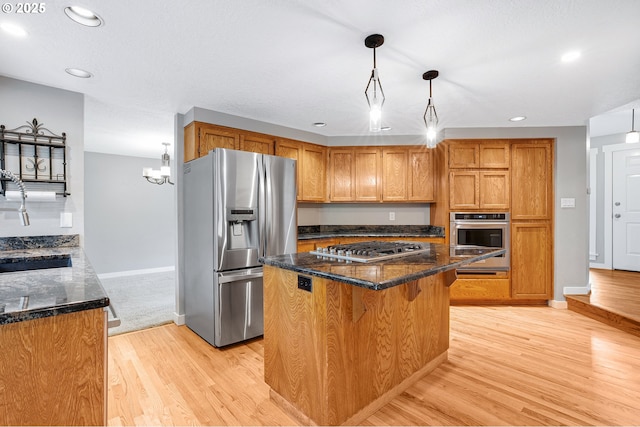 20752 SW 104th Ave, Tualatin, OR 97062 - kitchen featuring appliances with stainless steel finishes, recessed lighting, dark stone counters, light wood finished floors, and brown cabinetry
