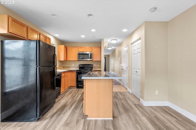 kitchen with light wood-type flooring, a kitchen island, baseboards, and black appliances
