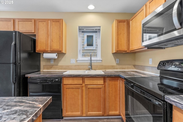 kitchen featuring recessed lighting, dark countertops, a sink, and black appliances