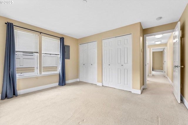 unfurnished bedroom featuring light colored carpet, baseboards, and multiple closets