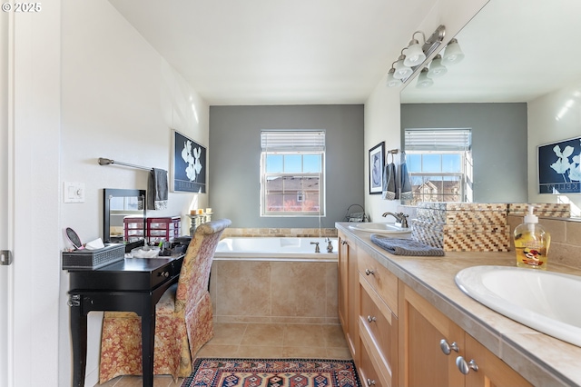 bathroom with tile patterned floors, a healthy amount of sunlight, tiled bath, and vanity