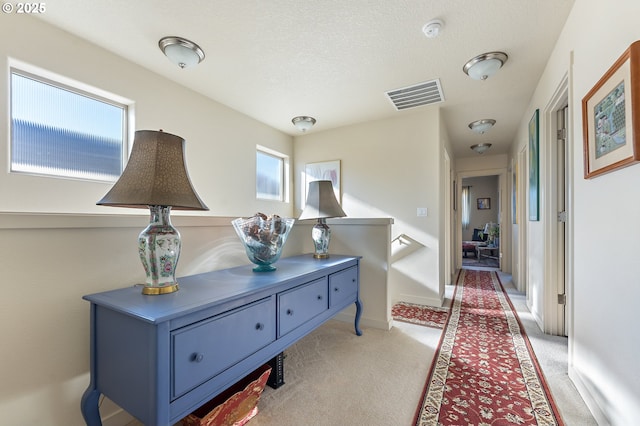 corridor featuring light colored carpet and a textured ceiling