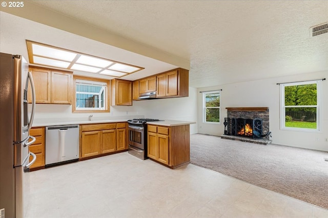 11347 SE Abby Ln, Clackamas, OR 97015 - kitchen with stainless steel appliances, open floor plan, light colored carpet, light countertops, and a stone fireplace