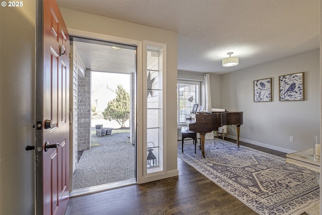 entrance foyer featuring a textured ceiling, baseboards, and dark wood-style flooring