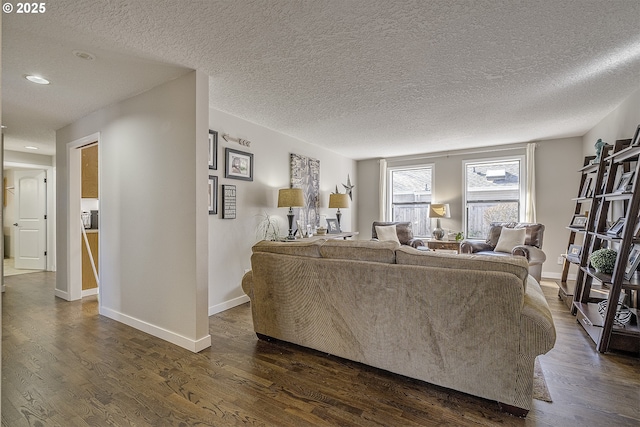 living area featuring baseboards, dark wood-style flooring, and a textured ceiling