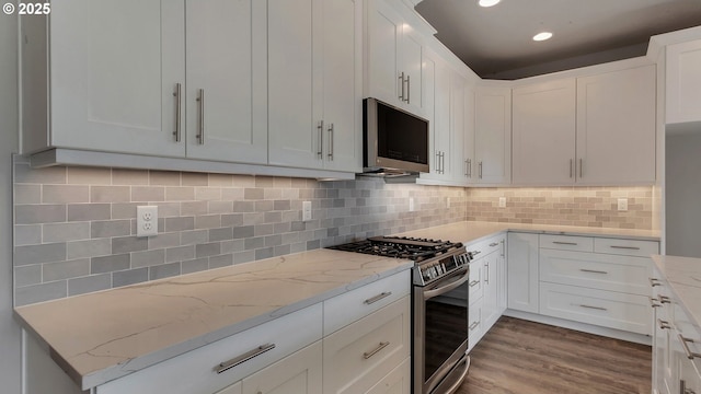 kitchen with white cabinets, light stone countertops, backsplash, and appliances with stainless steel finishes