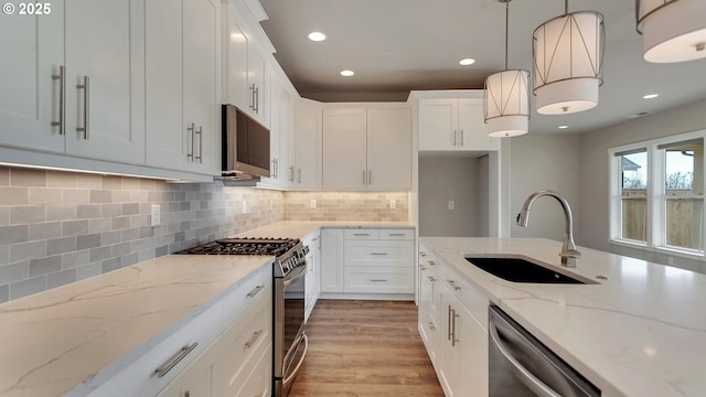 kitchen featuring white cabinets, appliances with stainless steel finishes, pendant lighting, and sink