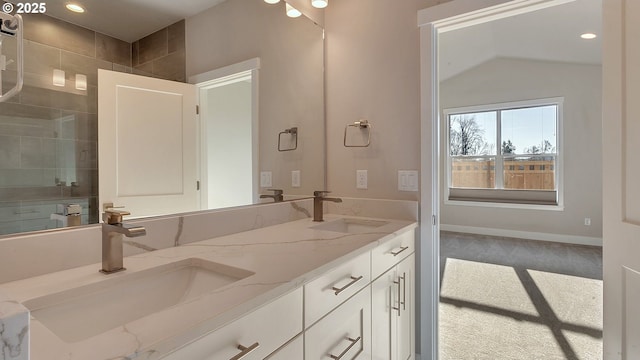 bathroom with a tile shower, vanity, and vaulted ceiling