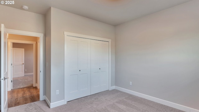 unfurnished bedroom with light colored carpet and a closet