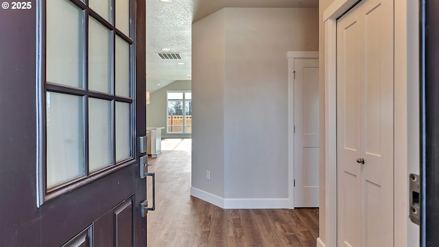 foyer entrance featuring lofted ceiling, hardwood / wood-style floors, and a textured ceiling