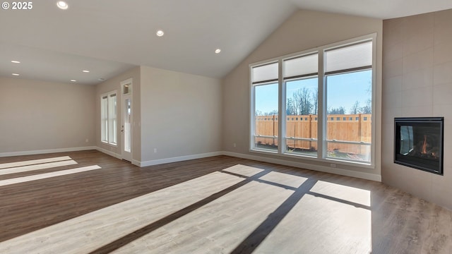 unfurnished living room with a tile fireplace, lofted ceiling, and dark wood-type flooring