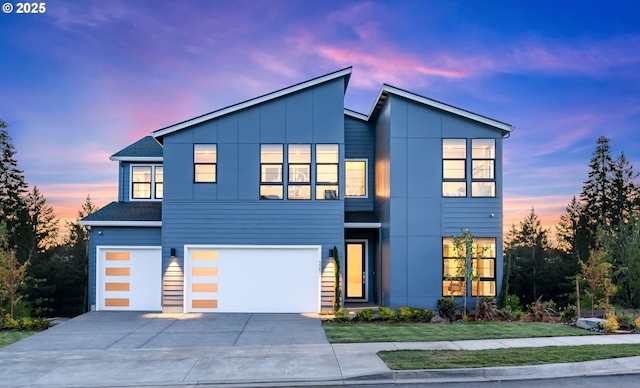 contemporary home with a garage, concrete driveway, roof with shingles, a front lawn, and board and batten siding