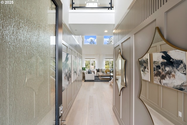 hallway with a decorative wall, a towering ceiling, and wood finished floors