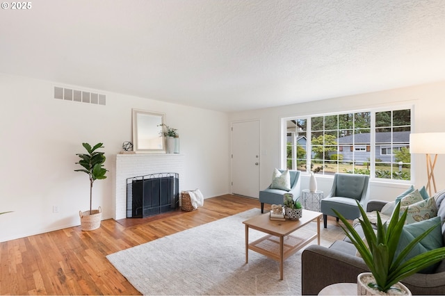 165 NE 167th Pl, Portland, OR 97230 - living room with a fireplace, wood finished floors, and a textured ceiling