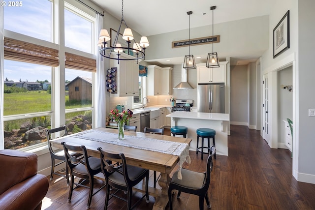 dining room featuring healthy amount of natural light, baseboards, a chandelier, dark wood-type flooring, and a towering ceiling