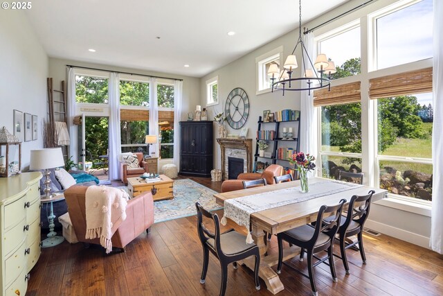dining room with a chandelier, hardwood / wood-style floors, a fireplace, recessed lighting, and baseboards