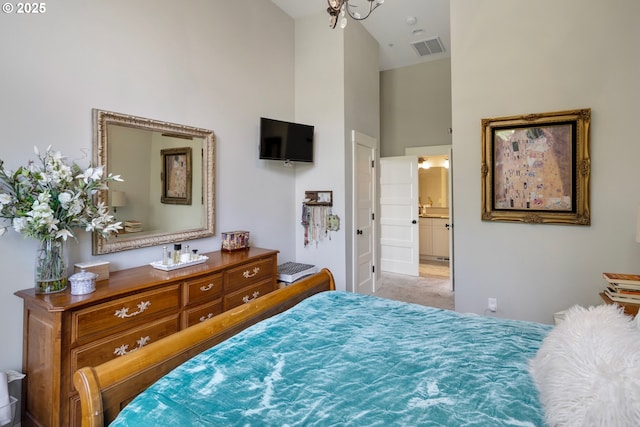 carpeted bedroom featuring a towering ceiling and ensuite bath