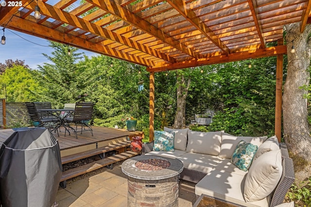 view of patio featuring an outdoor living space with a fire pit, outdoor dining area, a deck, a pergola, and view of wooded area