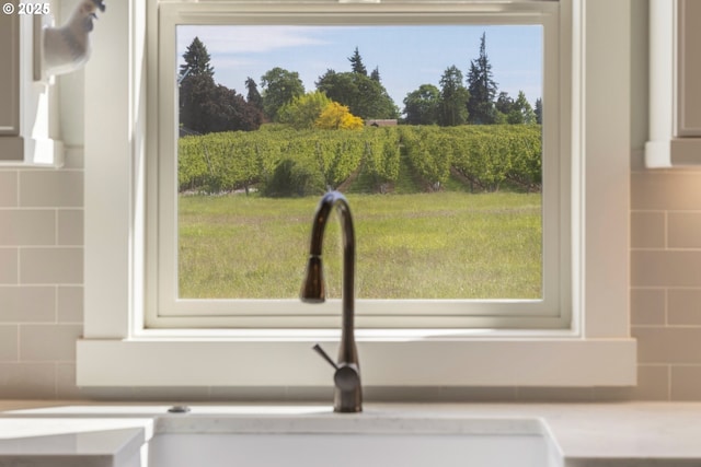kitchen view of decorative backsplash, light countertops, a sink, and white cabinets