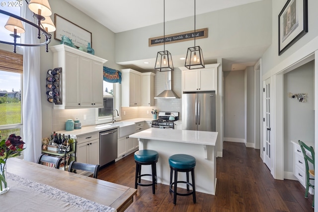 kitchen featuring stainless steel appliances, decorative backsplash, light countertops, dark wood finished floors, and a center island